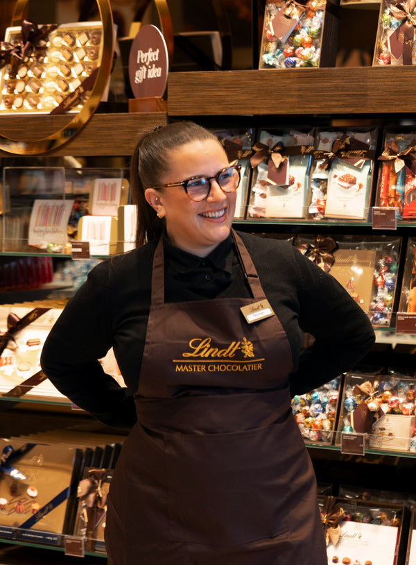 Person wearing a Lindt apron in a chocolate shop setting